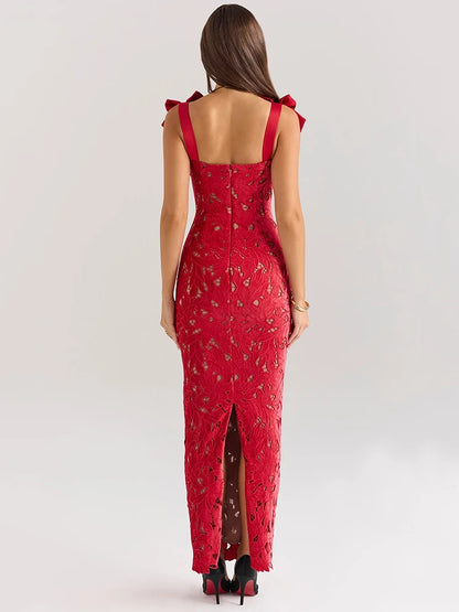 A woman wearing a red lace maxi dress with a fitted silhouette, bow-embellished straps, and a subtle back slit.