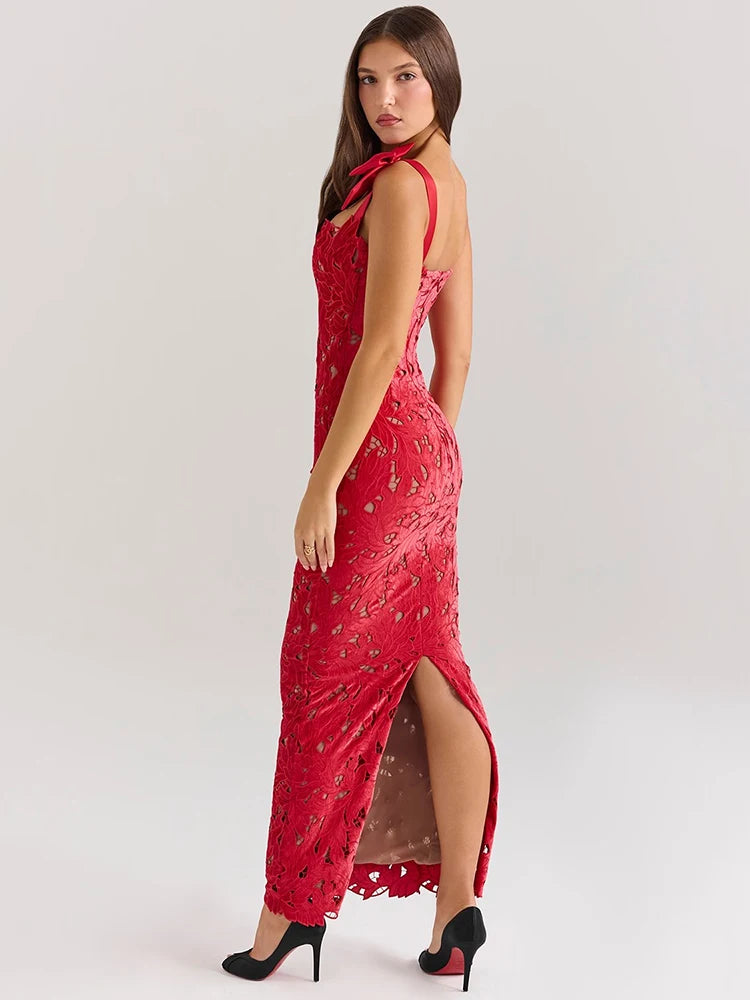 A woman wearing a red lace maxi dress with a fitted silhouette, bow-embellished straps, and a subtle back slit.