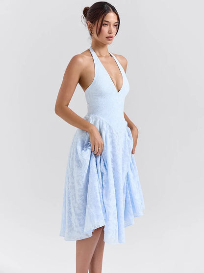 Woman wearing a Midi Dress in baby blue, showcasing the halter neck strap and soft A-line silhouette.