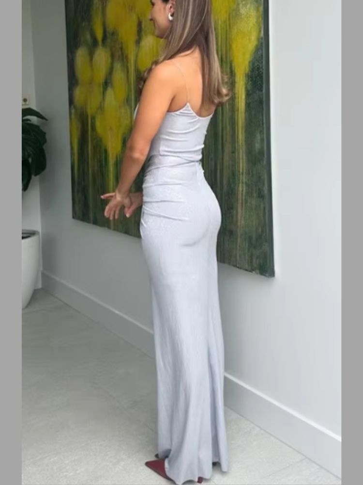 Woman wearing a Maxi Dress in silver, showcasing a metallic sheen, spaghetti straps, and ruched waist detailing.