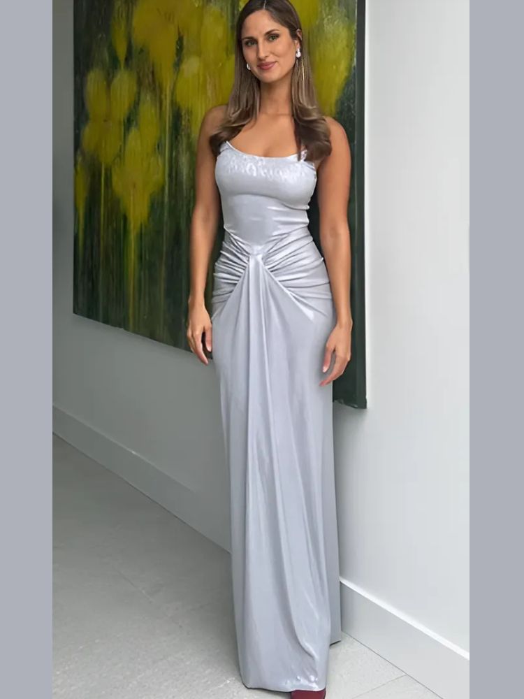 Woman wearing a Maxi Dress in silver, showcasing a metallic sheen, spaghetti straps, and ruched waist detailing.