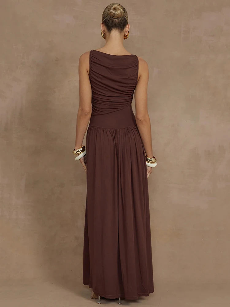 Woman wearing a sleeveless brown maxi dress with a boat neck design, ruched detailing, and long, flowy silhouette