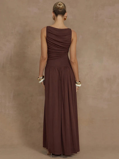 Woman wearing a sleeveless brown maxi dress with a boat neck design, ruched detailing, and long, flowy silhouette