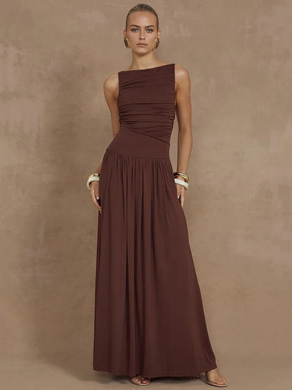 Woman wearing a sleeveless brown maxi dress with a boat neck design, ruched detailing, and long, flowy silhouette