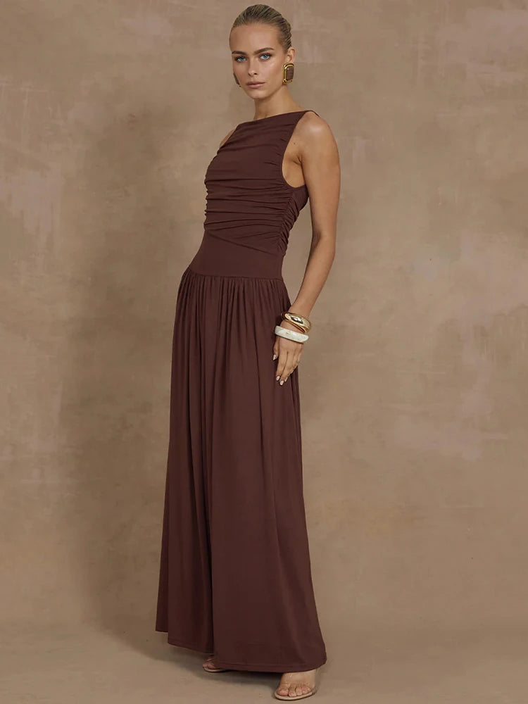 Woman wearing a sleeveless brown maxi dress with a boat neck design, ruched detailing, and long, flowy silhouette