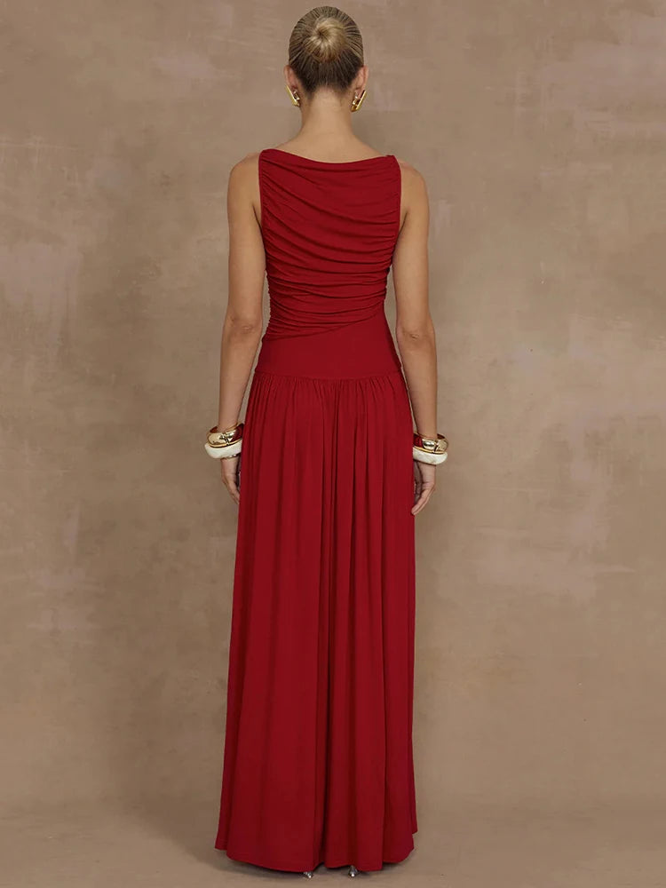 Woman wearing a sleeveless red maxi dress with a boat neck design, ruched detailing, and long, flowy silhouette