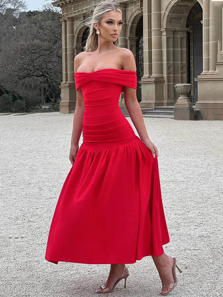 Woman wearing a red midaxi dress with a dropped waist, full gathered skirt, and pleated Bardot neckline, showcasing an elegant off-shoulder design