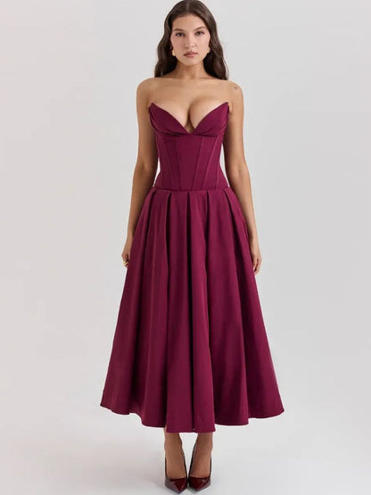 Woman wearing a wine red corset V-neck sleeveless maxi dress with chest-wrapping detail, high waist A-line skirt, fit and flare silhouette, and ankle-length design