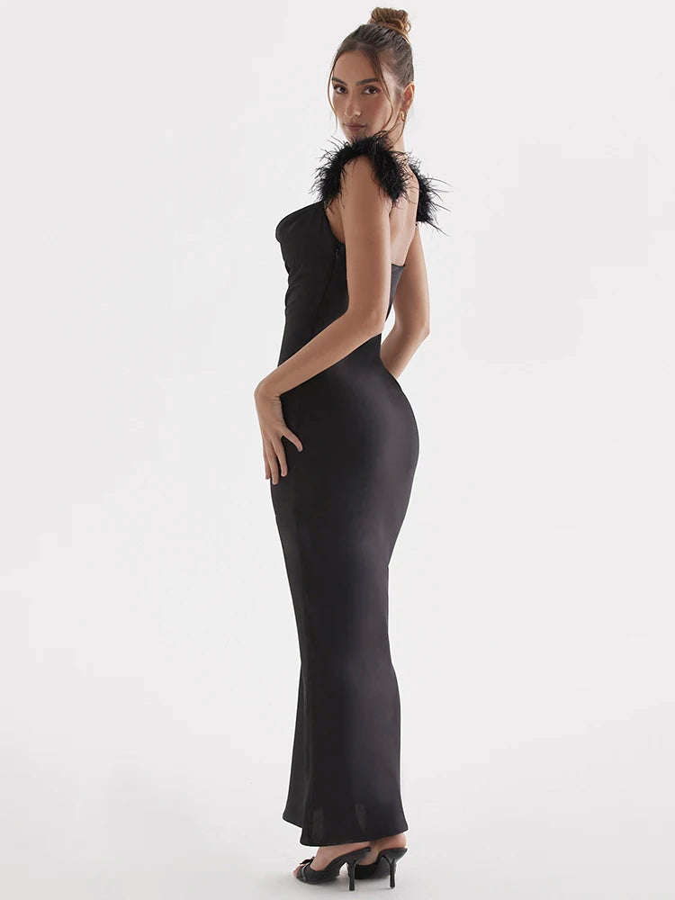 Woman wearing a Black satin maxi dress with feather spaghetti straps, sleeveless and backless design, bodycon fit