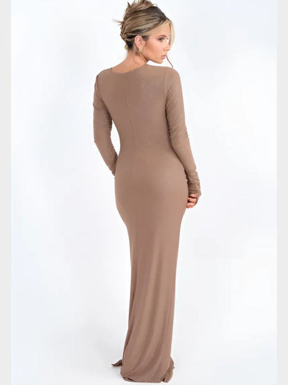 Woman wearing a sparkly beige asymmetrical maxi dress with long sleeves, ruched details, and a draped hemline.