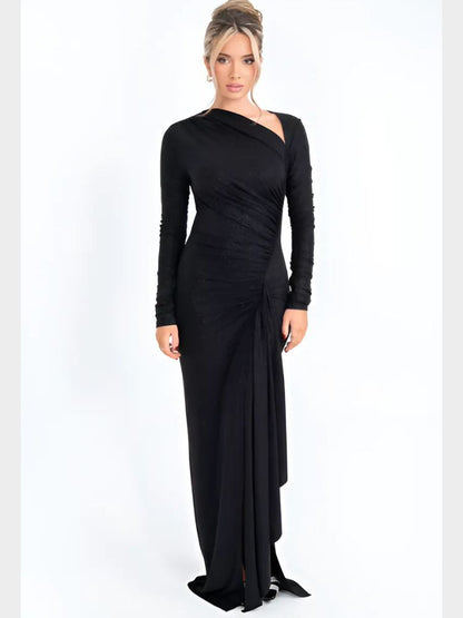 Woman wearing a sparkly black asymmetrical maxi dress with long sleeves, ruched details, and a draped hemline.