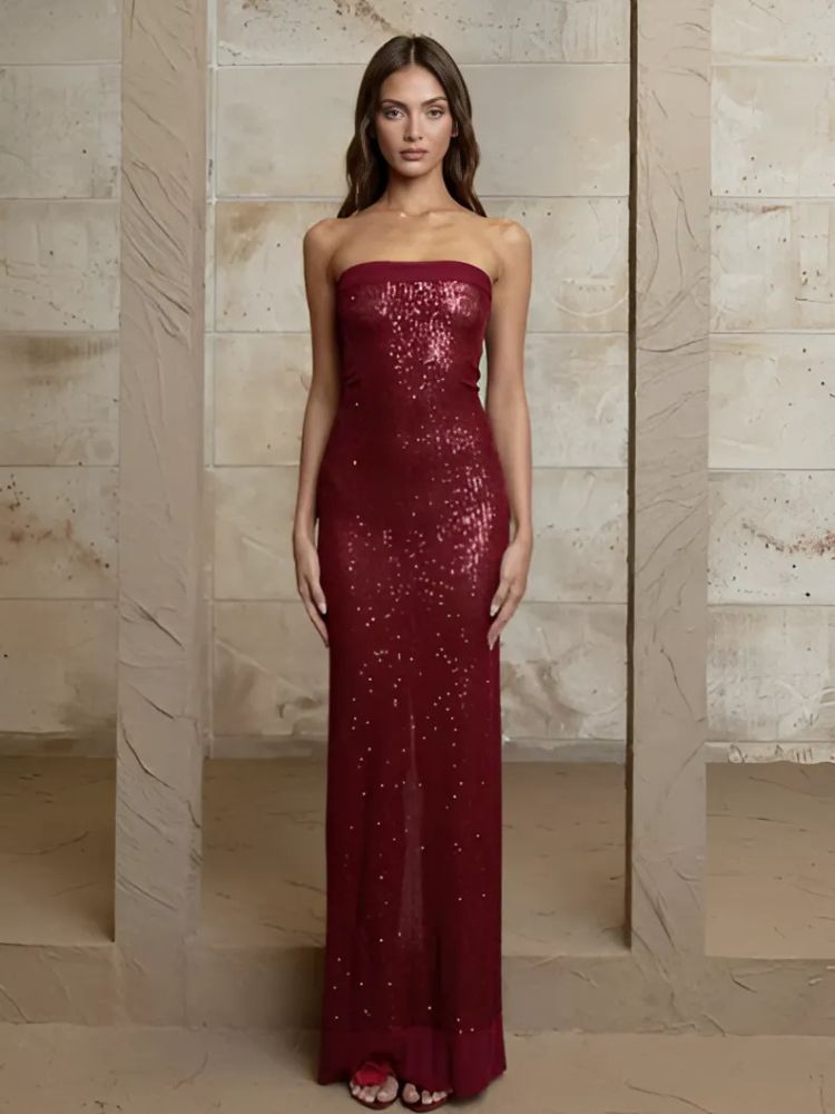 A woman wearing the Marylin Maxi Dress in deep red, featuring dazzling sequins, a strapless neckline, and a back slit