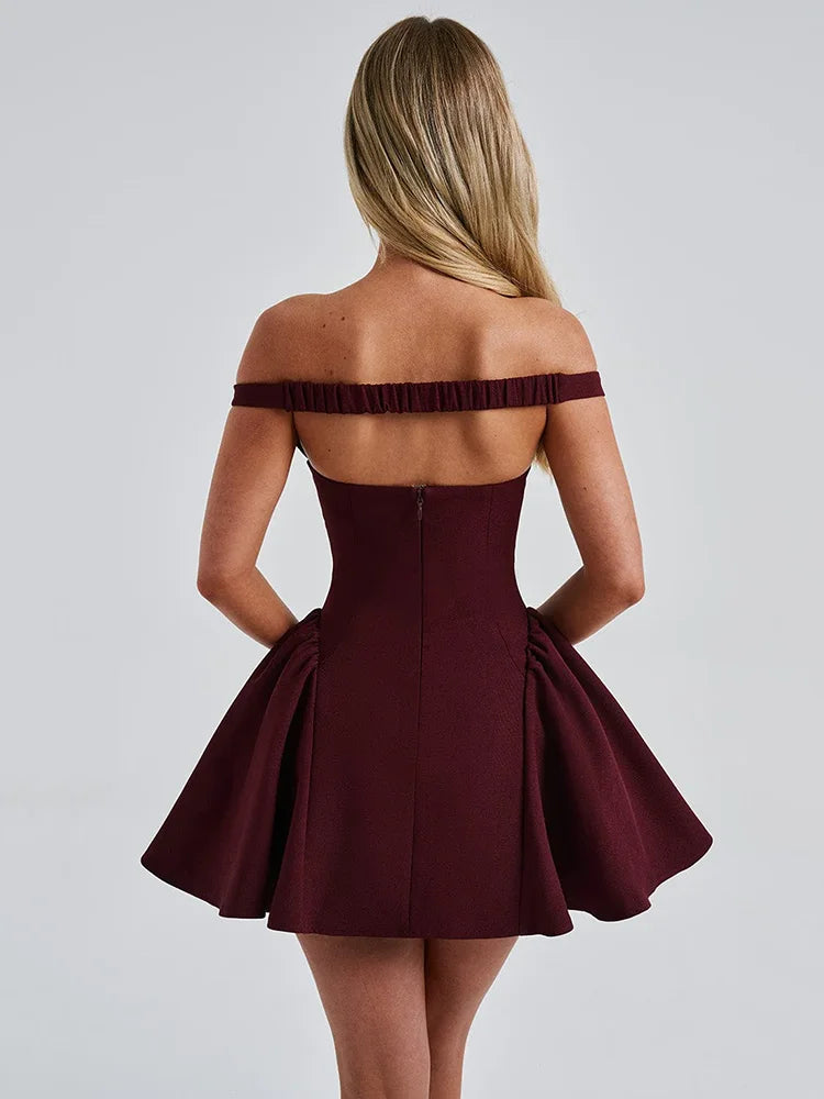 Woman wearing a wine-red off-shoulder mini dress with a plunge Bardot neckline, elasticated back strap, backless design, high waist, and A-line silhouette.