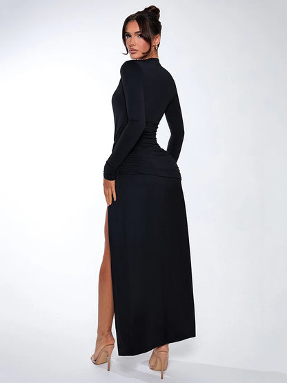 Woman wearing a black long-sleeved maxi dress with deep V-neck, thigh-high split, and ruched knot detailing