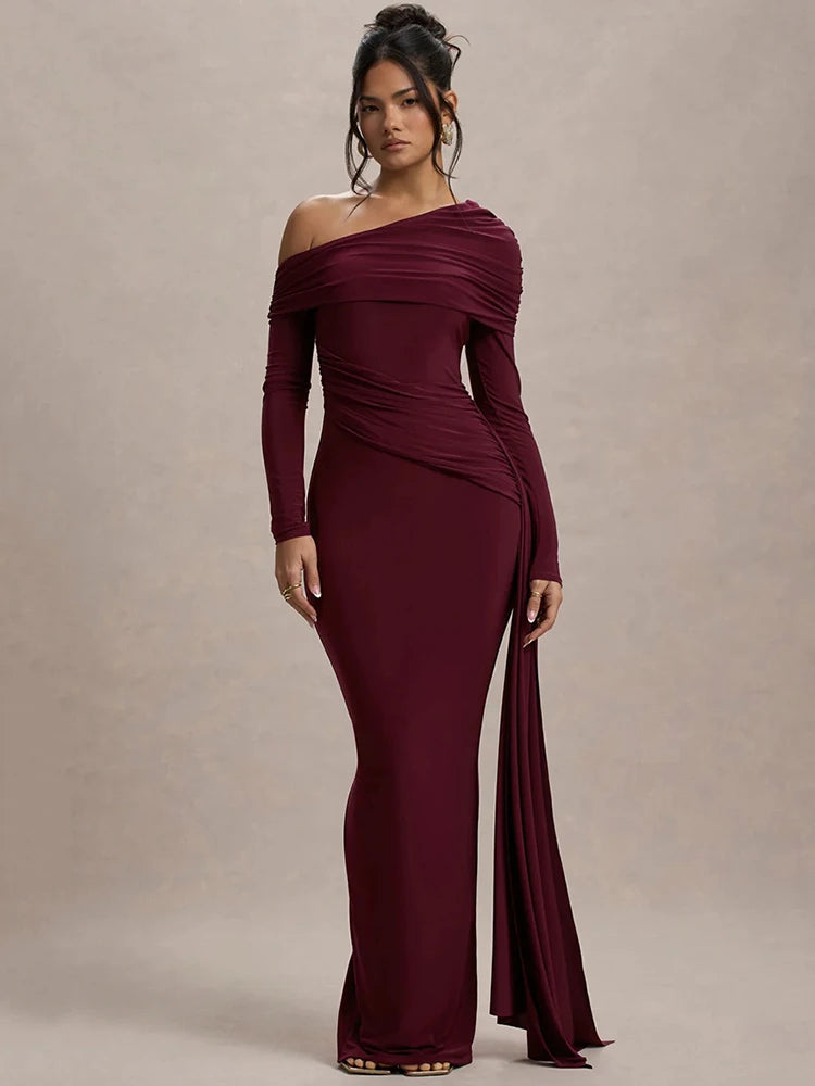 Woman wearing a wine red one-shoulder maxi dress with gathered detailing, draped sash, and a sleek, fitted silhouette