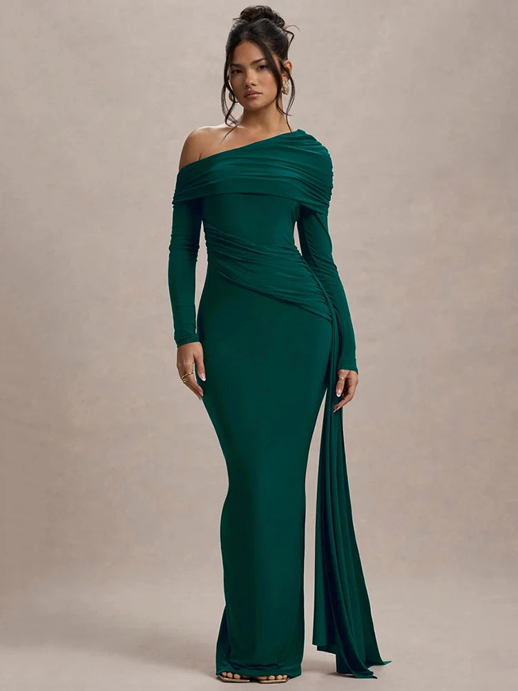 Woman wearing a dark green one-shoulder maxi dress with gathered detailing, draped sash, and a sleek, fitted silhouette