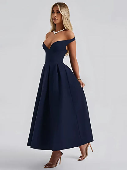 A woman wearing a navy off shoulder midaxi dress with a pleated skirt