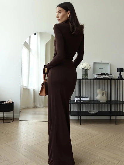 Woman wearing a brown maxi dress  with a turtleneck, thigh-high split, long sleeves, draped hips and a bodycon fit