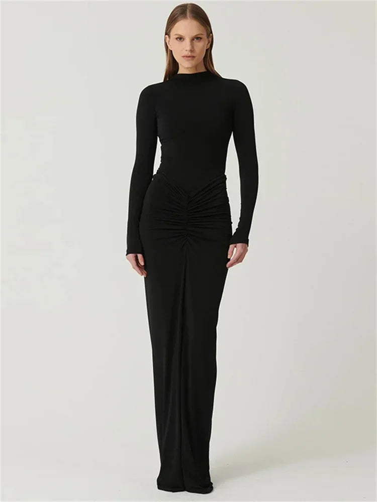 Woman wearing a Black Floor-length bodycon dress with long sleeves, high collar, O-neck, high waist, pleated hip detail, and invisible zipper