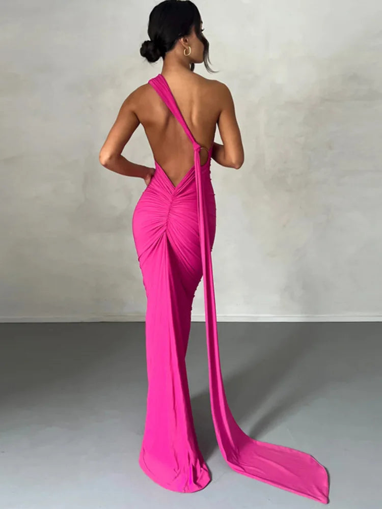 Pink bodycon maxi dress with a backless design, oblique shoulder, ruched detailing, and strap accents. Features a trumpet/mermaid silhouette, strapless neckline, and off-the-shoulder sleeves.