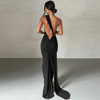 Black bodycon maxi dress with a backless design, oblique shoulder, ruched detailing, and strap accents. Features a trumpet/mermaid silhouette, strapless neckline, and off-the-shoulder sleeves.