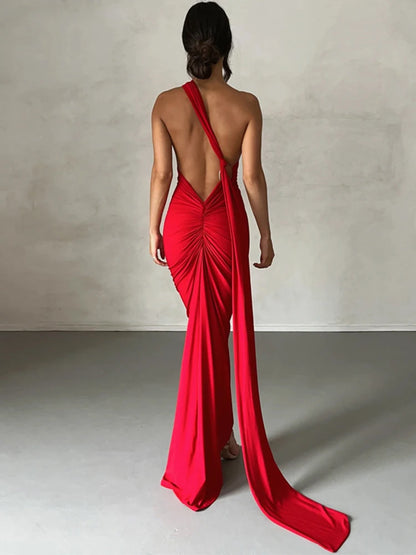 Red bodycon maxi dress with a backless design, oblique shoulder, ruched detailing, and strap accents. Features a trumpet/mermaid silhouette, strapless neckline, and off-the-shoulder sleeves.