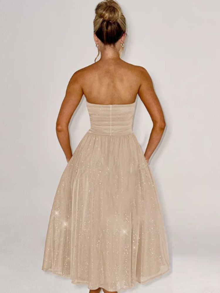 Woman wearing a strapless beige midi dress with glitter accents and a flowy skirt.