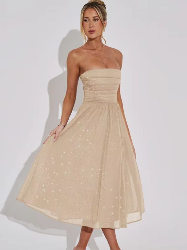 Woman wearing a strapless beige midi dress with glitter accents and a flowy skirt.