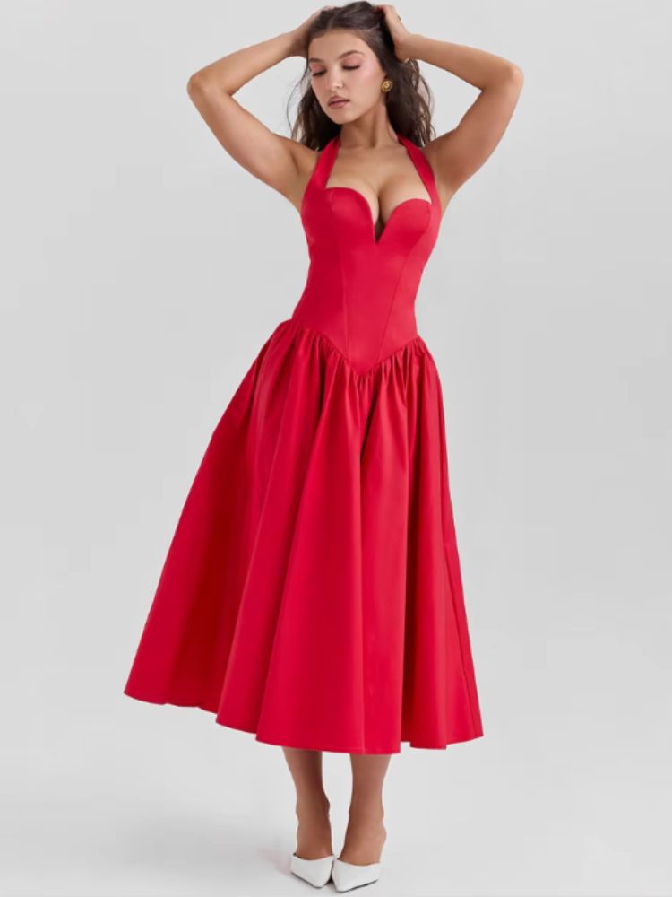 Woman wearing a red midaxi dress with a deep halter v neck, pleated skirt an neck mounted backless design.