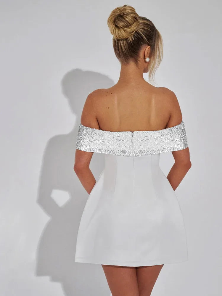 A woman wearing a white off-shoulder mini dress with a sparkling sequined neckline and an A-line silhouette.