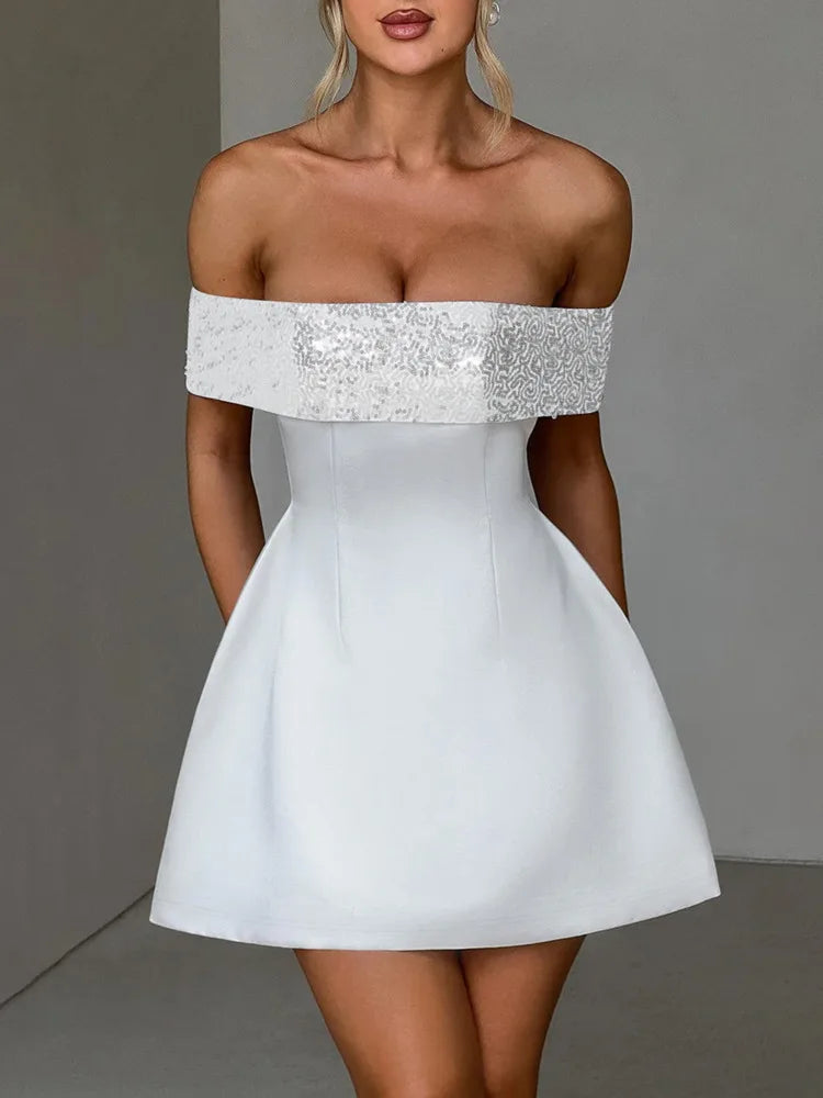 A woman wearing a white off-shoulder mini dress with a sparkling sequined neckline and an A-line silhouette.