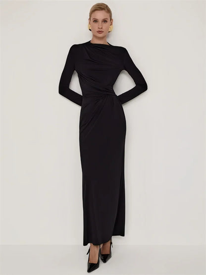 Woman wearing a black maxi dress with long sleeve, pleated, O-neck, ankle-length  and stretchy fabric